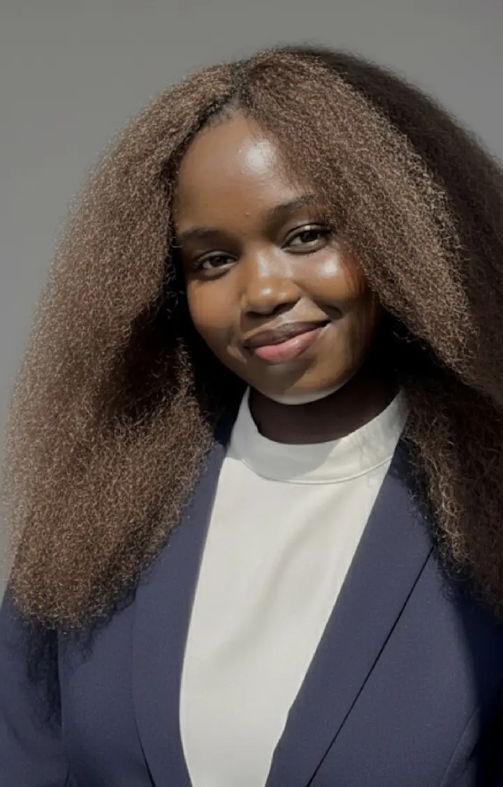 Portrait of Annlidya, smiling, wearing a navy blazer over a cream top